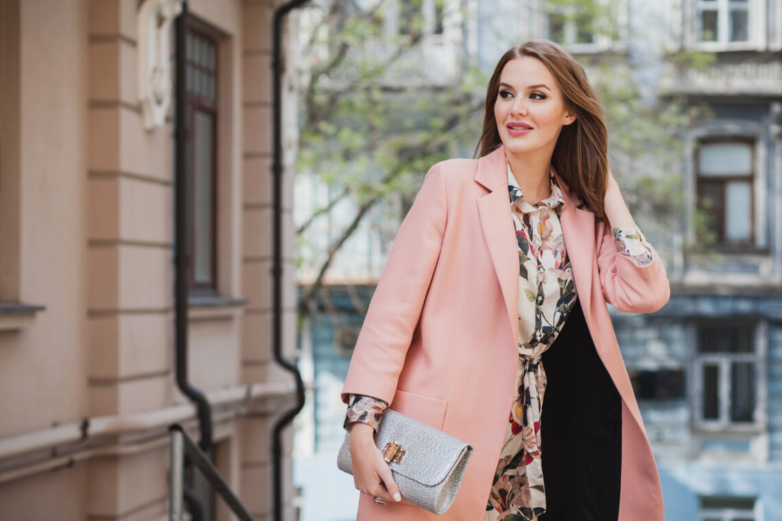 A lady in pink long blazer and off white gown.